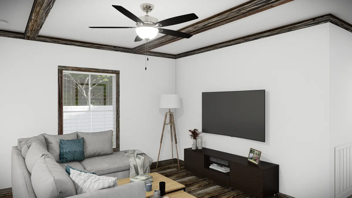 A modern living room with a gray sectional sofa, a flat-screen TV on a dark console, a floor lamp, a window, and a ceiling fan with lights.