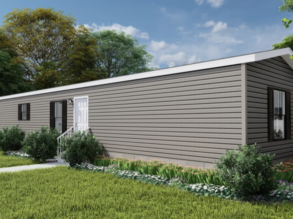 A single-story, gray manufactured home with a white door and windows, surrounded by green grass, shrubs, and trees under a partly cloudy sky.