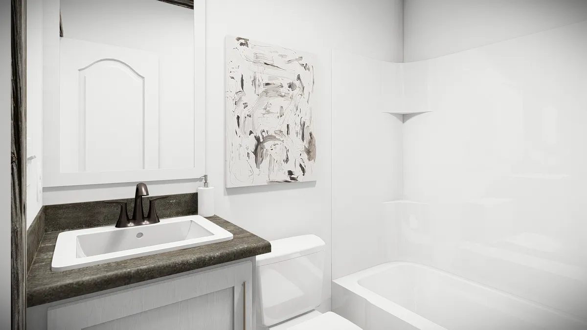 Small modern bathroom with a sink, black faucet, mirror, abstract wall art, toilet, and a white bathtub with a curved shower wall.