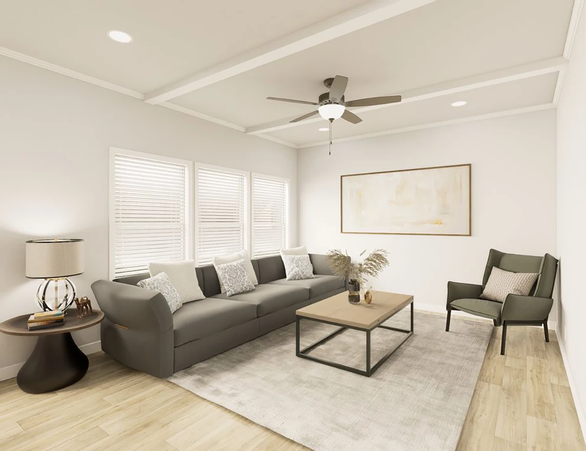 The Elite 52 19 Modern living room with a gray sofa, armchair, light wood coffee table, round side table with a lamp, large rug, and a ceiling fan. Three windows and a framed artwork on the wall.