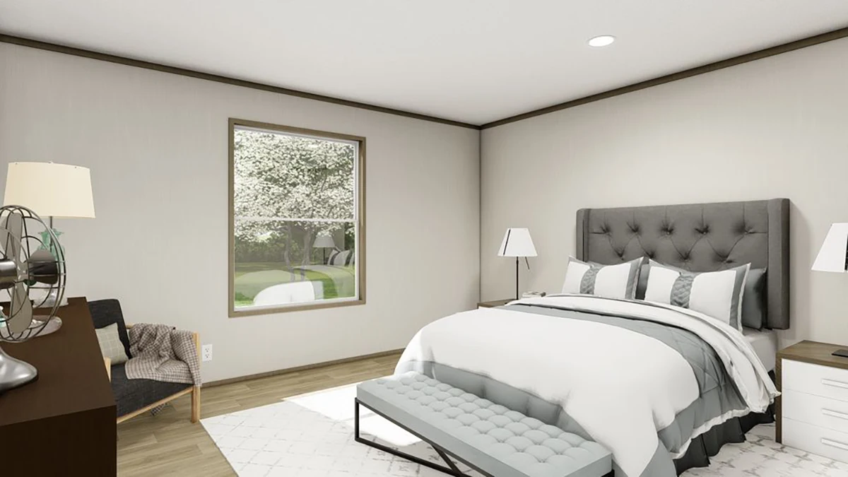 a5c24e59-ebea-4072-ac83-80148a78612d A modern bedroom with a gray upholstered bed, white bedding, a bench at the foot, two bedside lamps, a window with a view of trees, and neutral-colored walls and flooring.