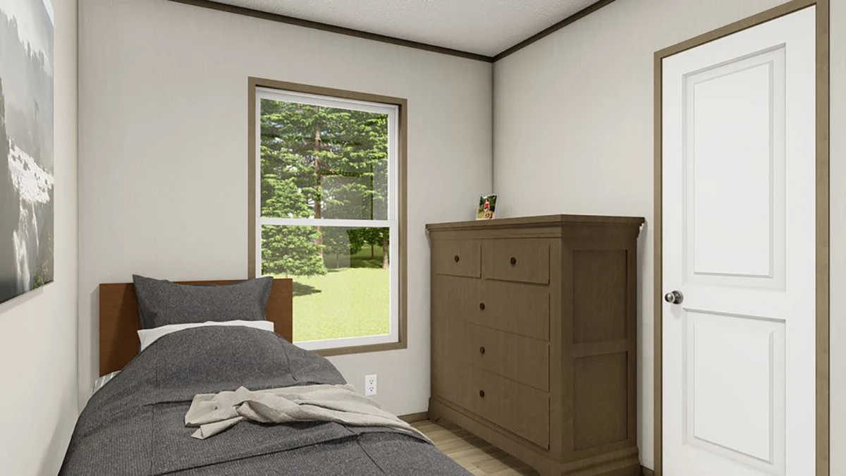 a7a49114-cf73-4c3f-87e7-f5e96351fd1e A small bedroom with a single bed, gray bedding, a brown dresser, a door, and a window showing green trees outside.