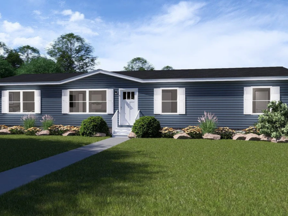 A single-story, blue manufactured home with white trim, a central front door, and a landscaped yard with shrubs and rocks under a partly cloudy sky.