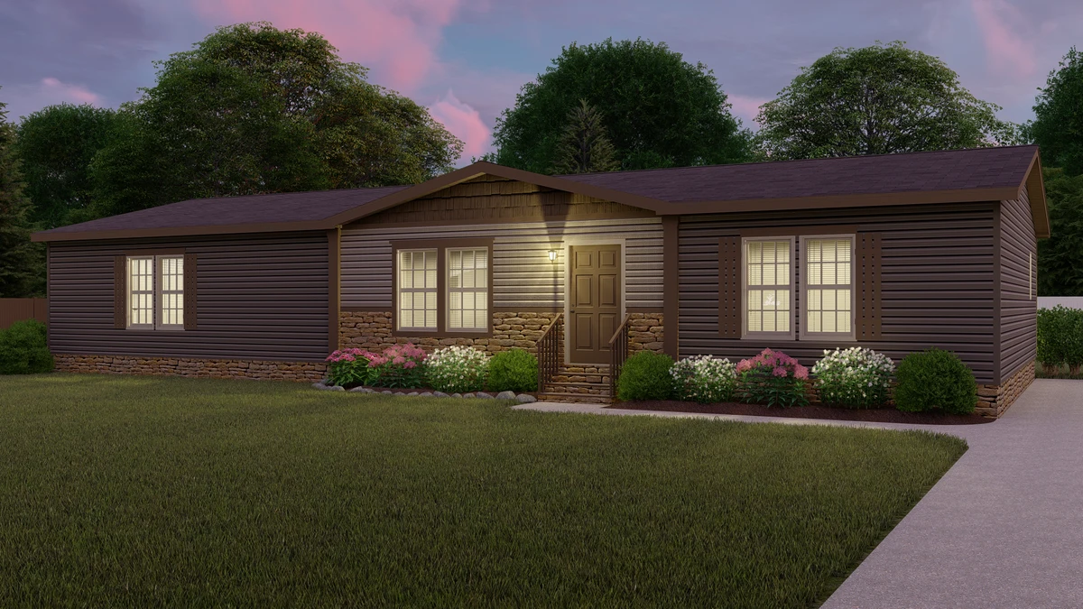 af87a56f-eda1-490e-bfd1-7a78652a1763 Single-story manufactured home with brown siding, stone accents, lit windows, and a central front door, surrounded by bushes and flowers, with a lawn and driveway.