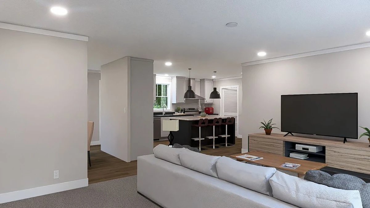 A modern open-plan living room with a light sofa, TV on a wooden stand, kitchen with island seating, and pendant lights in the background.