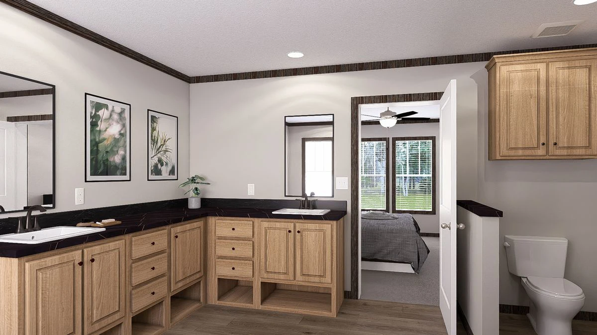 afc25beb-8696-4f0f-a936-16ffd7aca1a3 Modern bathroom with light wood cabinets, black countertops, two sinks, mirror, wall art, a toilet, and a view into a bedroom with large windows.