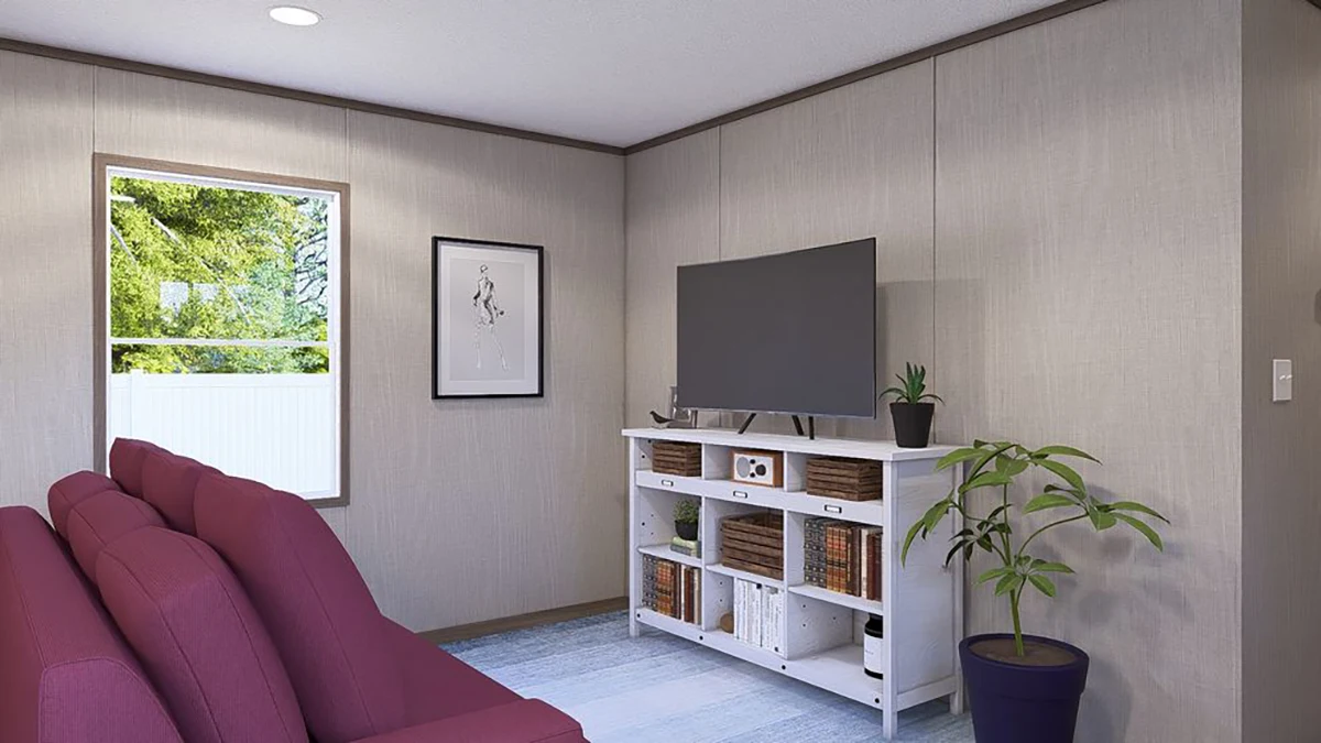 A living room with a maroon sofa, a TV on a white stand, a potted plant, a framed picture on the wall, and a window showing trees outside.