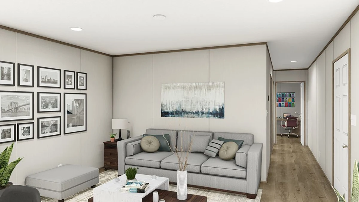 b1e441cc-d9f2-437b-9252-8b00765b36bb Modern living room with a gray sofa, a coffee table, framed pictures on the wall, plants, and a view into a hallway with a desk and chair in the background.