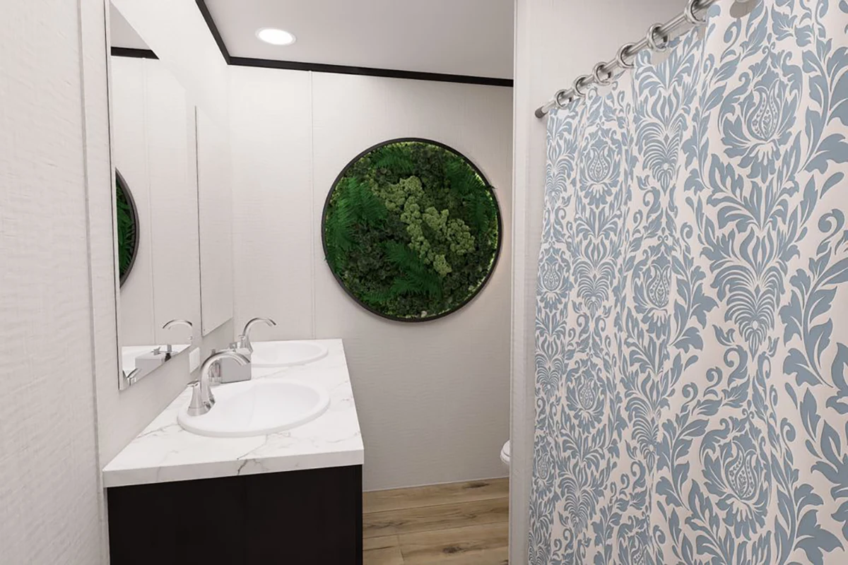 b26b0a00-9624-452c-a71e-1ec492abd549 A modern bathroom with double sinks, a marble countertop, a round green plant wall art, wood flooring, and a shower with a blue and white patterned curtain.