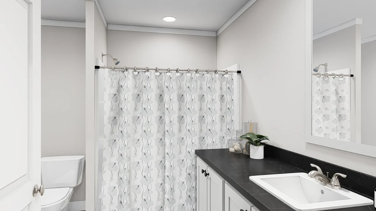 b3158d7c-29ca-4101-b006-bb8b255a3cfd A modern bathroom with a white toilet, a shower with a patterned curtain, a black countertop with a white sink, and beige walls.