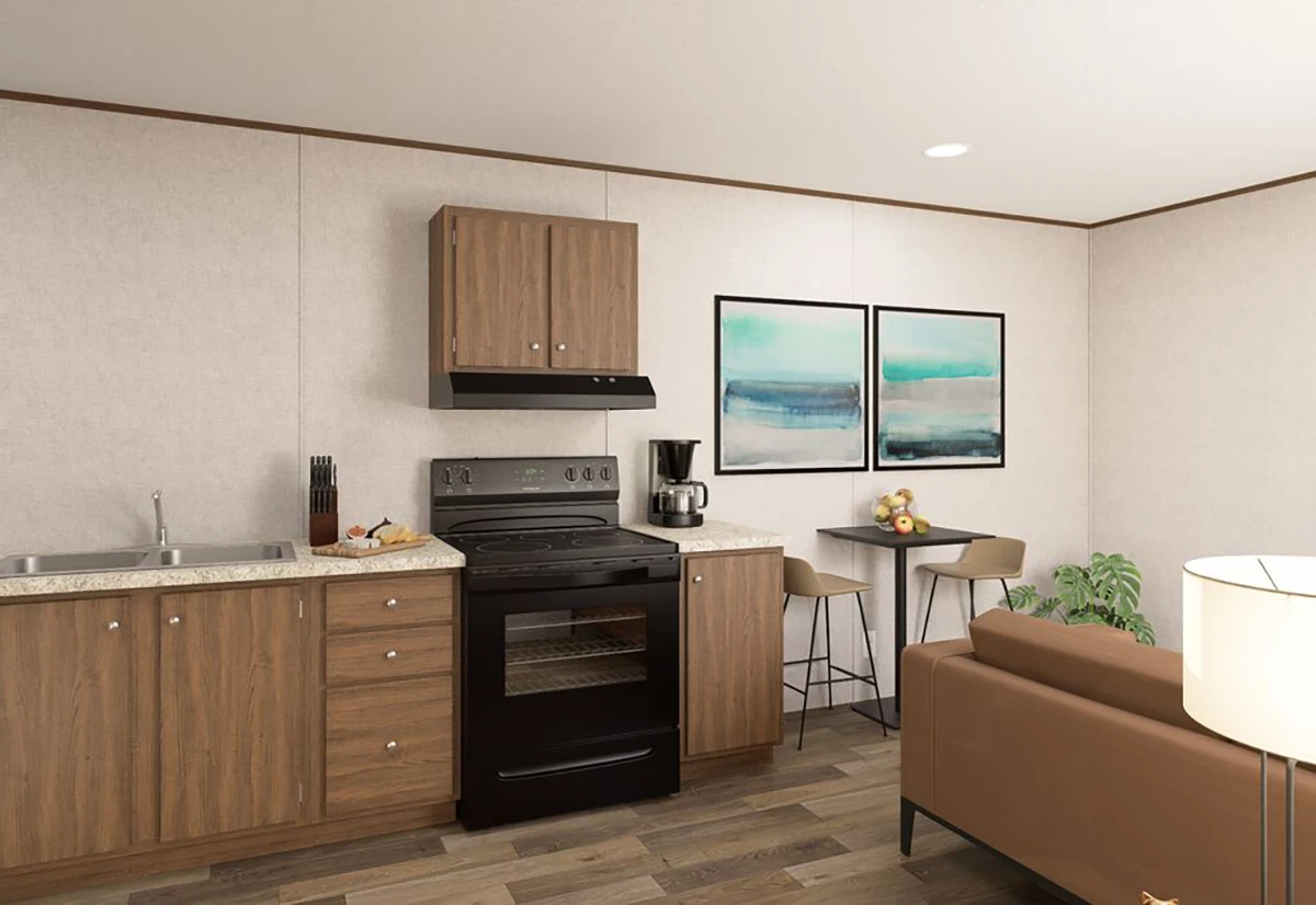 A small kitchen with wood cabinets, a black stove, a sink, a coffee maker, a knife block, and a small dining area with two chairs and abstract artwork on the wall.