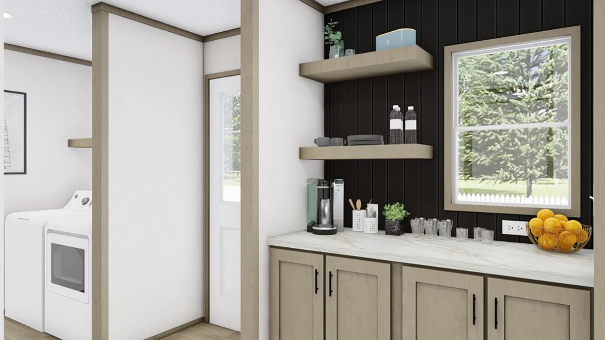 Laundry area with washer and dryer next to a countertop with a coffee maker, shelves holding dishes and bottles, and a bowl of oranges, set against black and white walls.
