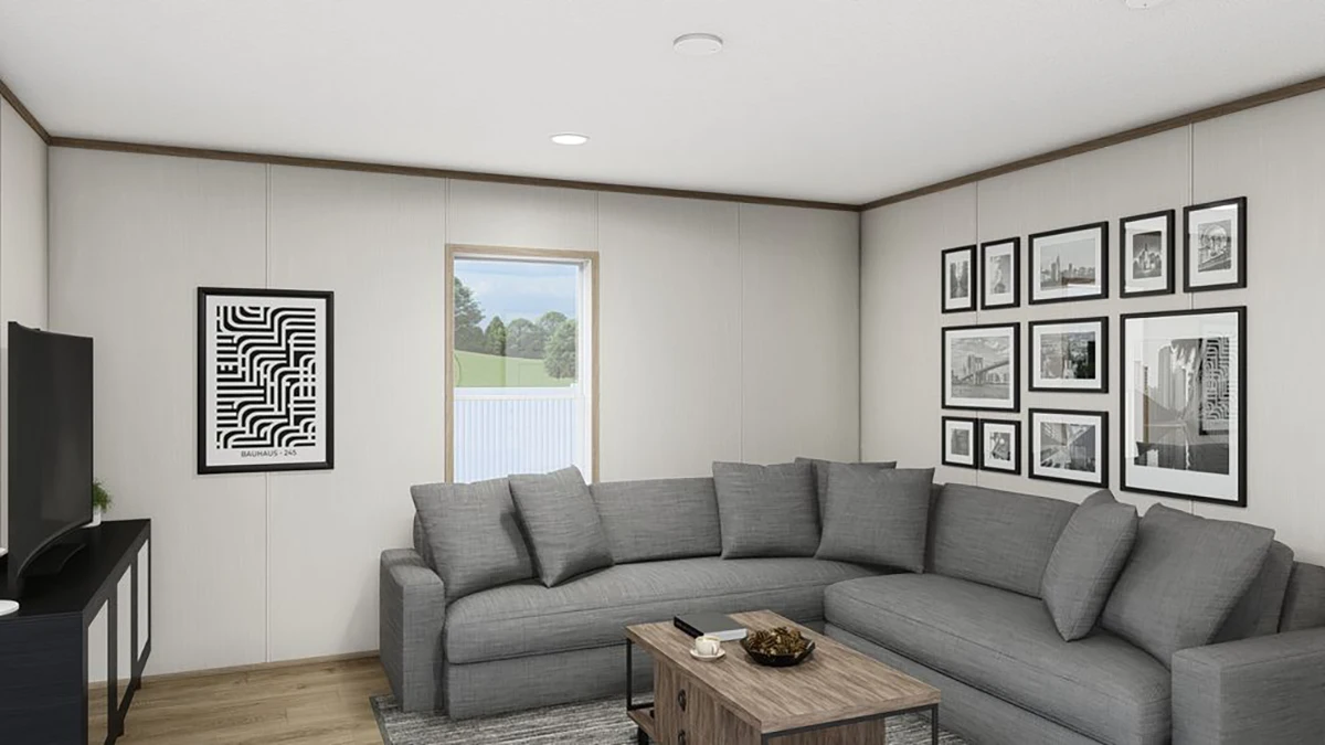 A modern living room with a gray sectional sofa, a wood coffee table, framed artwork on the walls, a TV on a stand, and a window showing trees outside.