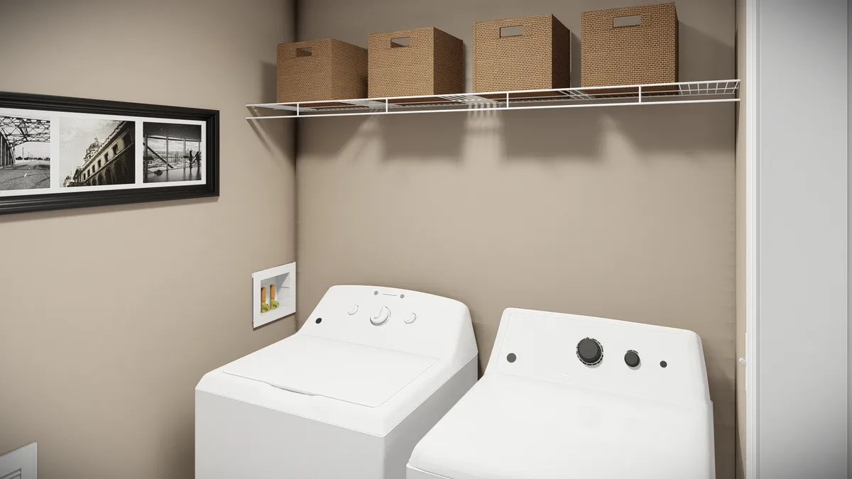 c2e22c40-5583-4745-9ebf-74db3fcc7563 Laundry room with a washing machine and dryer side by side, four wicker baskets on a wire shelf above, and framed pictures on a beige wall.