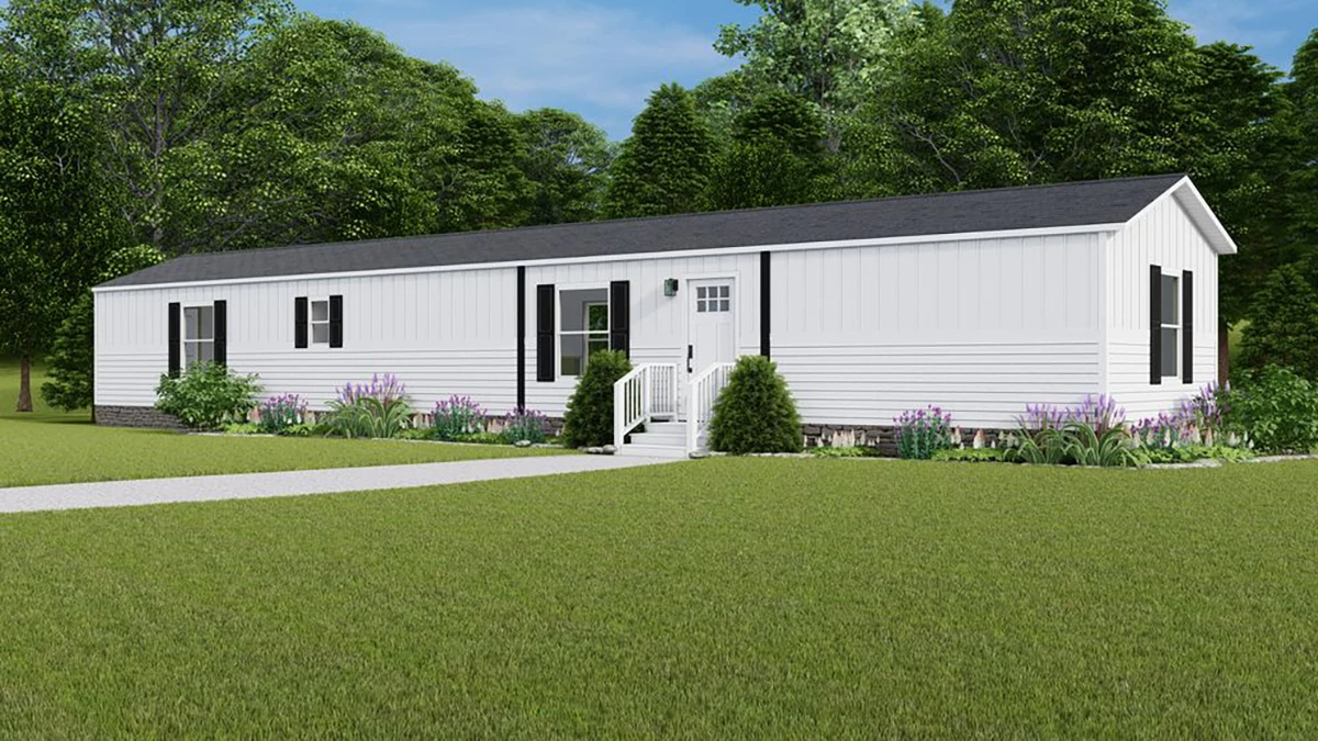 c4119067-7d84-45cc-8cee-3bce74043f45 A white single-wide manufactured home with black shutters, a small front porch with steps, and surrounding landscaping, set on a grassy lawn with trees in the background.