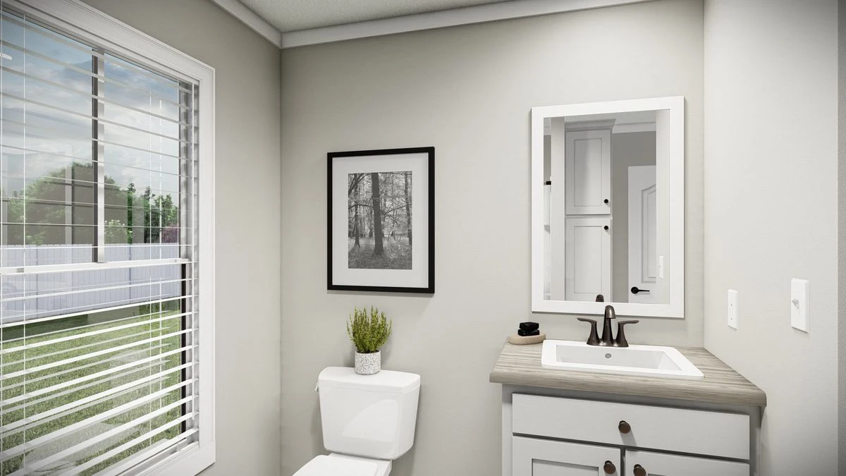 c649bae3-40a1-4758-87f8-df42920389c7 A bathroom with a window, toilet, potted plant, framed picture, vanity with sink, and a mirror above the countertop.