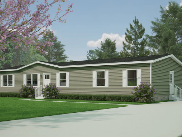 A green manufactured home with white trim, multiple windows, two small porches with railings, set on a grassy lawn with trees and a paved driveway.