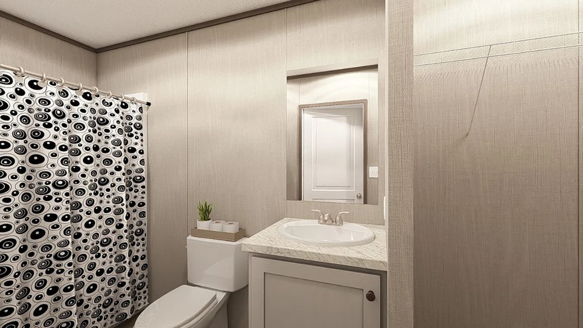 A bathroom with a toilet, a small plant on the tank, a sink with a marble countertop, a mirror, and a shower with a black and white patterned curtain.
