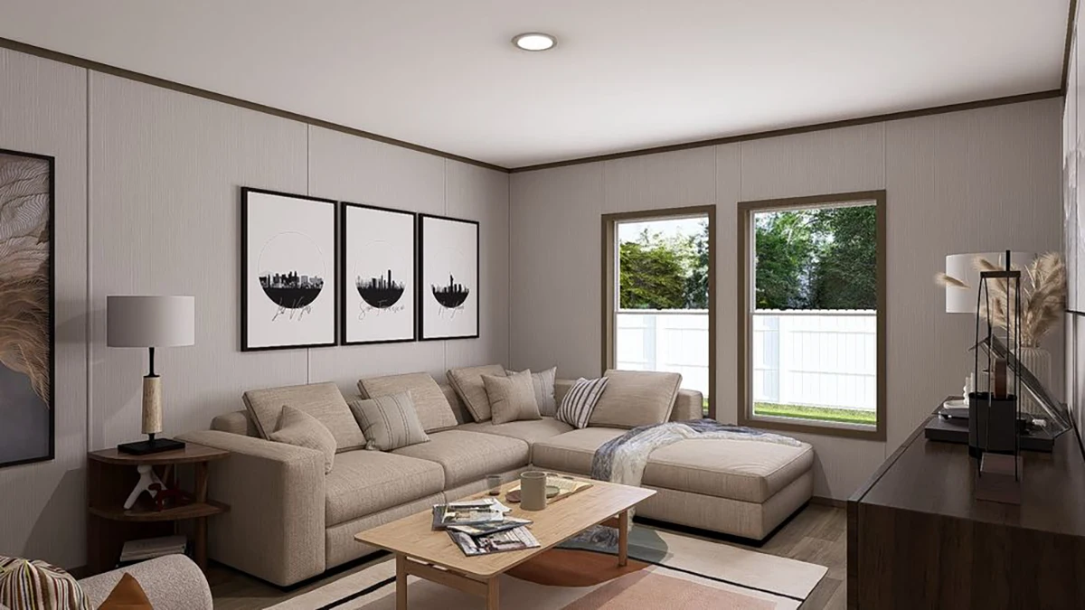 Modern living room with a beige sectional sofa, three black-and-white art pieces on the wall, a wooden coffee table, a TV, and large windows showing a fenced yard.