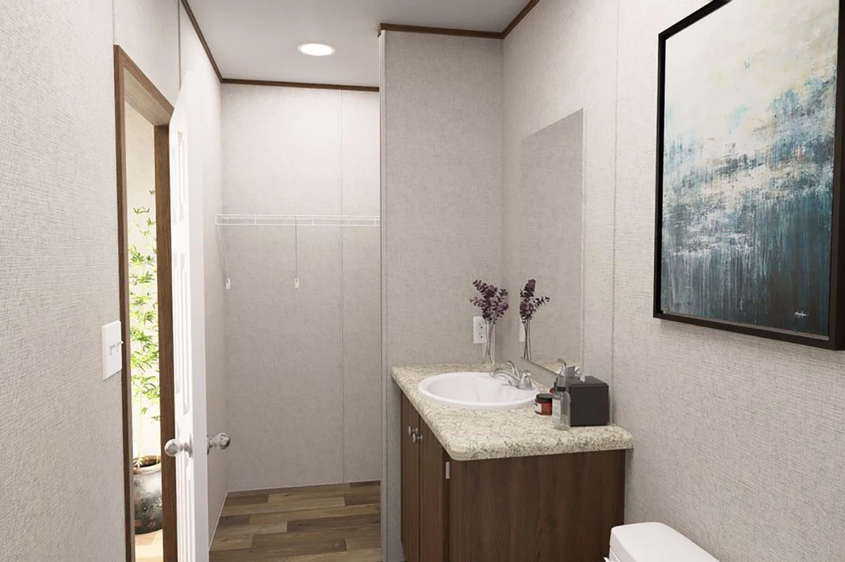d4ca4865-addd-49c1-82b6-03185bb5ced3 A small bathroom with beige walls, a countertop sink with cabinets, a wall mirror, decorative items, and an abstract painting above the toilet.