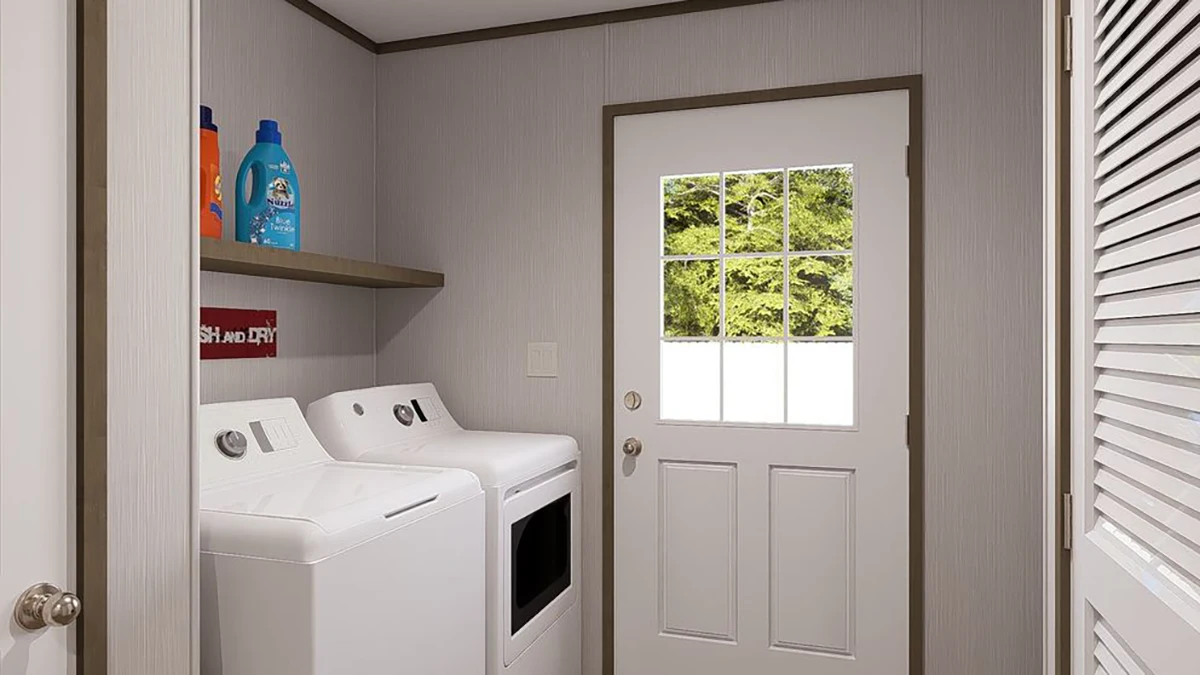 A laundry room with a washing machine and dryer, detergent bottles on a shelf above, and a door with a window leading outside.