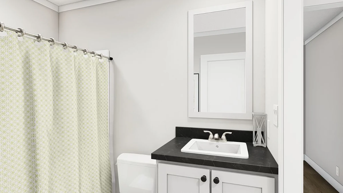 A bathroom with a white sink, black countertop, mirror above the vanity, toilet, and a shower with a patterned curtain.