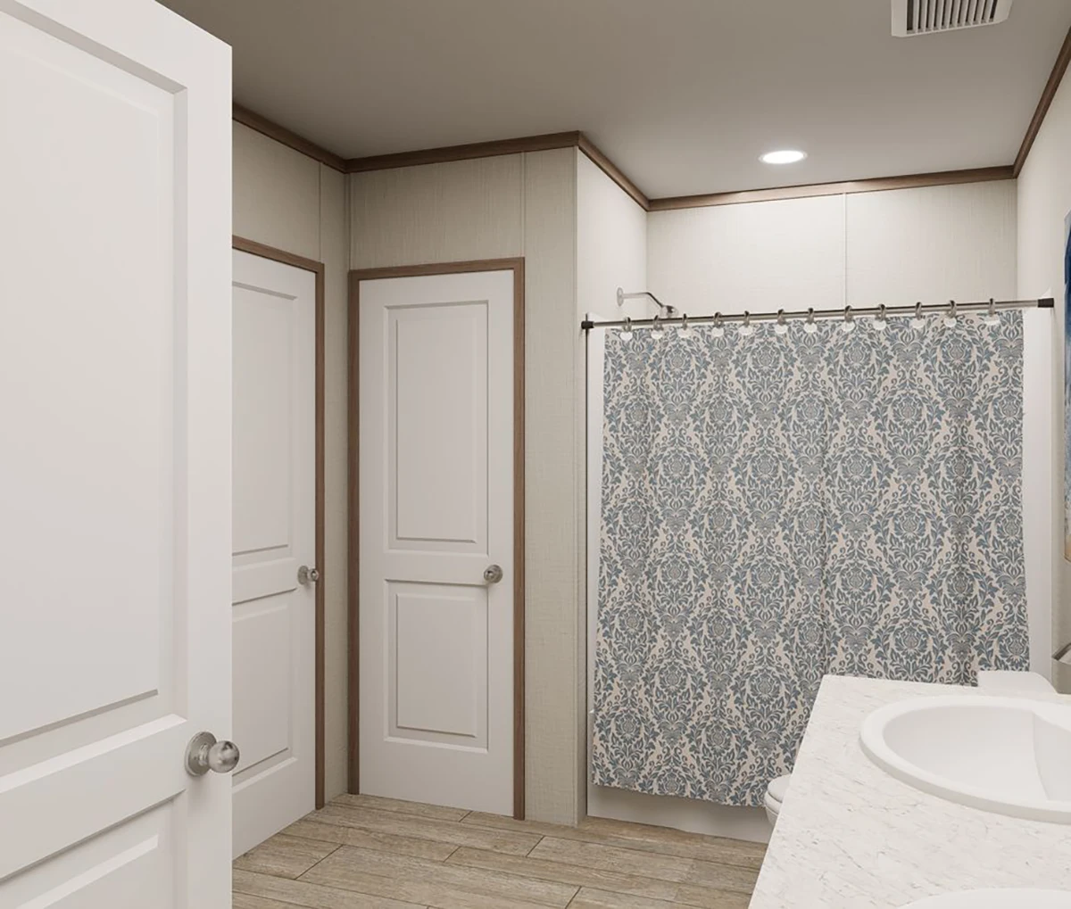 Modern bathroom with light wood flooring, two white doors, a white vanity with sinks, and a blue patterned shower curtain.