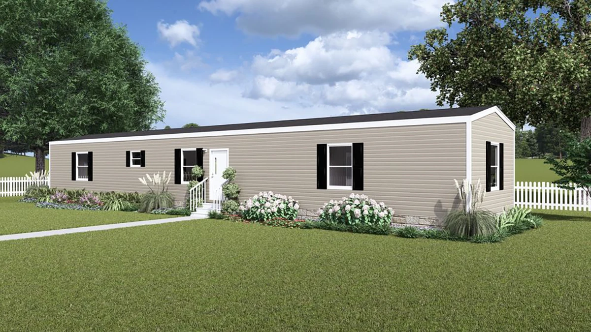 da871917-67f4-454b-b7a9-6ad2dd6141be A beige manufactured home with black shutters, white trim, front steps, and landscaping, set on a grassy lawn with a white picket fence and trees in the background.