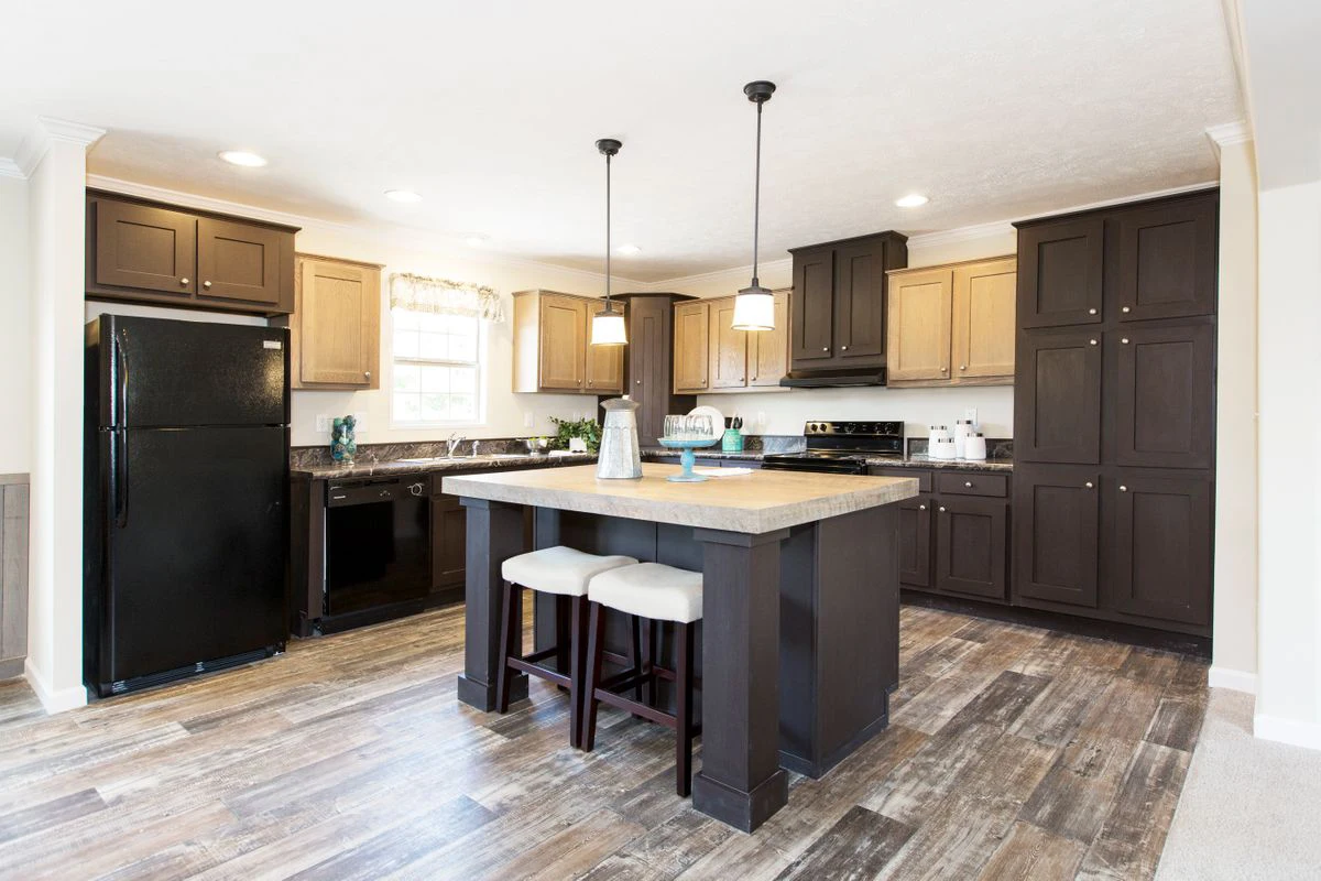 dc61b51e-39f0-419b-a27b-02c5aa9e92f2 Modern kitchen with dark and light brown cabinets, black appliances, an island with two stools, and wood-look flooring under recessed and pendant lighting.