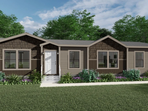 A brown, single-story modular home with a white front door, multiple windows, and landscaped shrubs, set against a backdrop of green trees and blue sky.