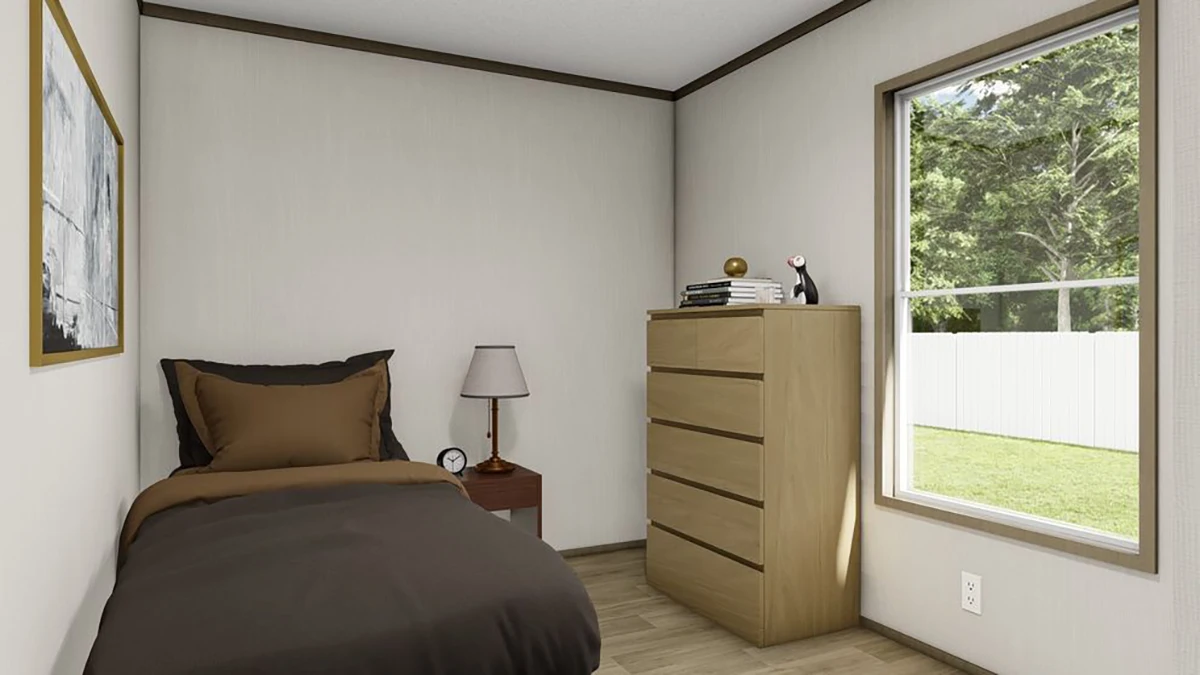 A small bedroom with a single bed, bedside table with a lamp and clock, a dresser with books and decor, and a window showing a green yard.