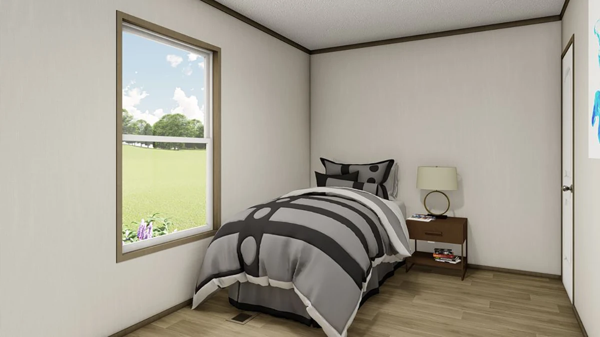 A small bedroom with a single bed, geometric-patterned bedding, a nightstand with a lamp, and a window showing a grassy view.