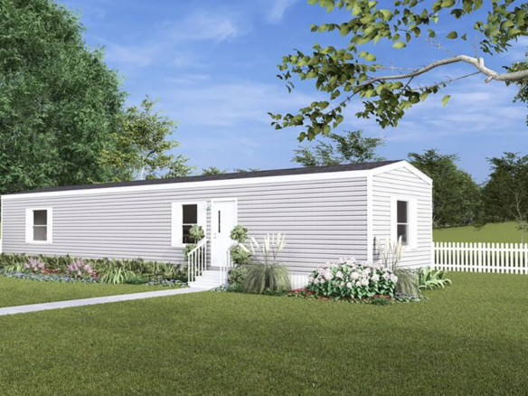 A single-story manufactured home with white siding, surrounded by a white picket fence, landscaped garden, and green lawn under a blue sky.