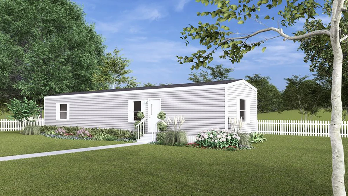 e50a5fa0-b0d1-4e02-9172-3bf010412645 A single-story manufactured home with white siding, surrounded by a white picket fence, landscaped garden, and green lawn under a blue sky.
