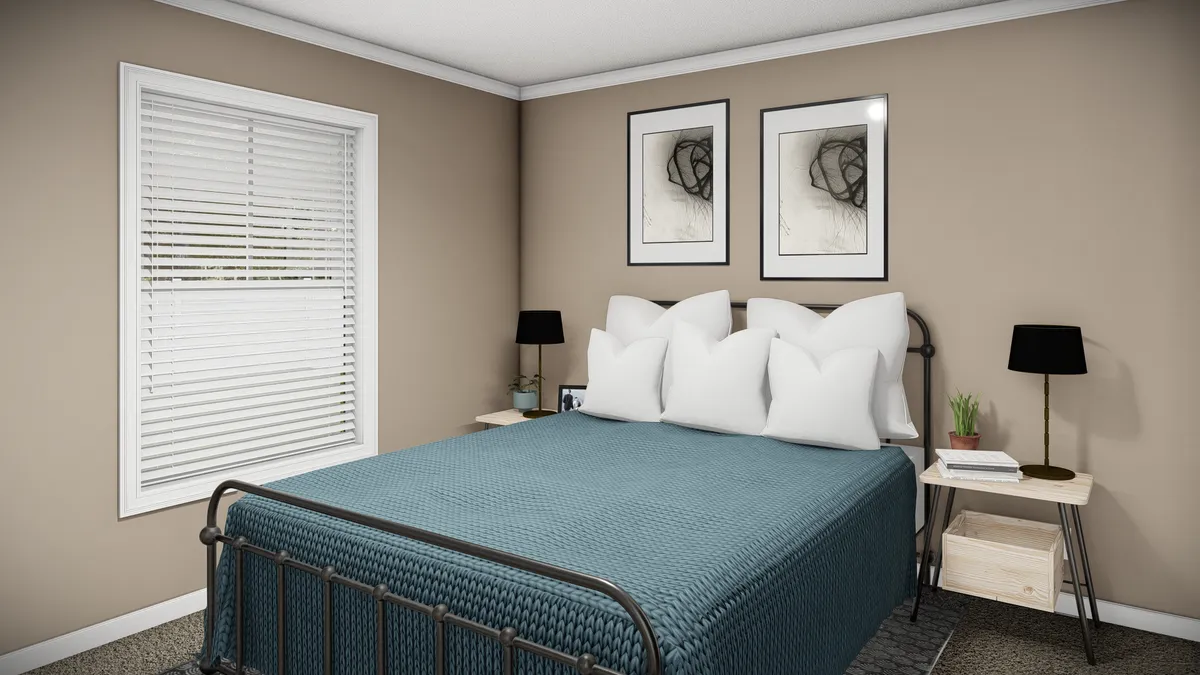e5c0c005-d1f0-4b2e-bcc3-1070bcfc4130 A neatly made bed with a blue blanket, four white pillows, two black lamps, framed abstract art, and a window with closed blinds in a beige bedroom.