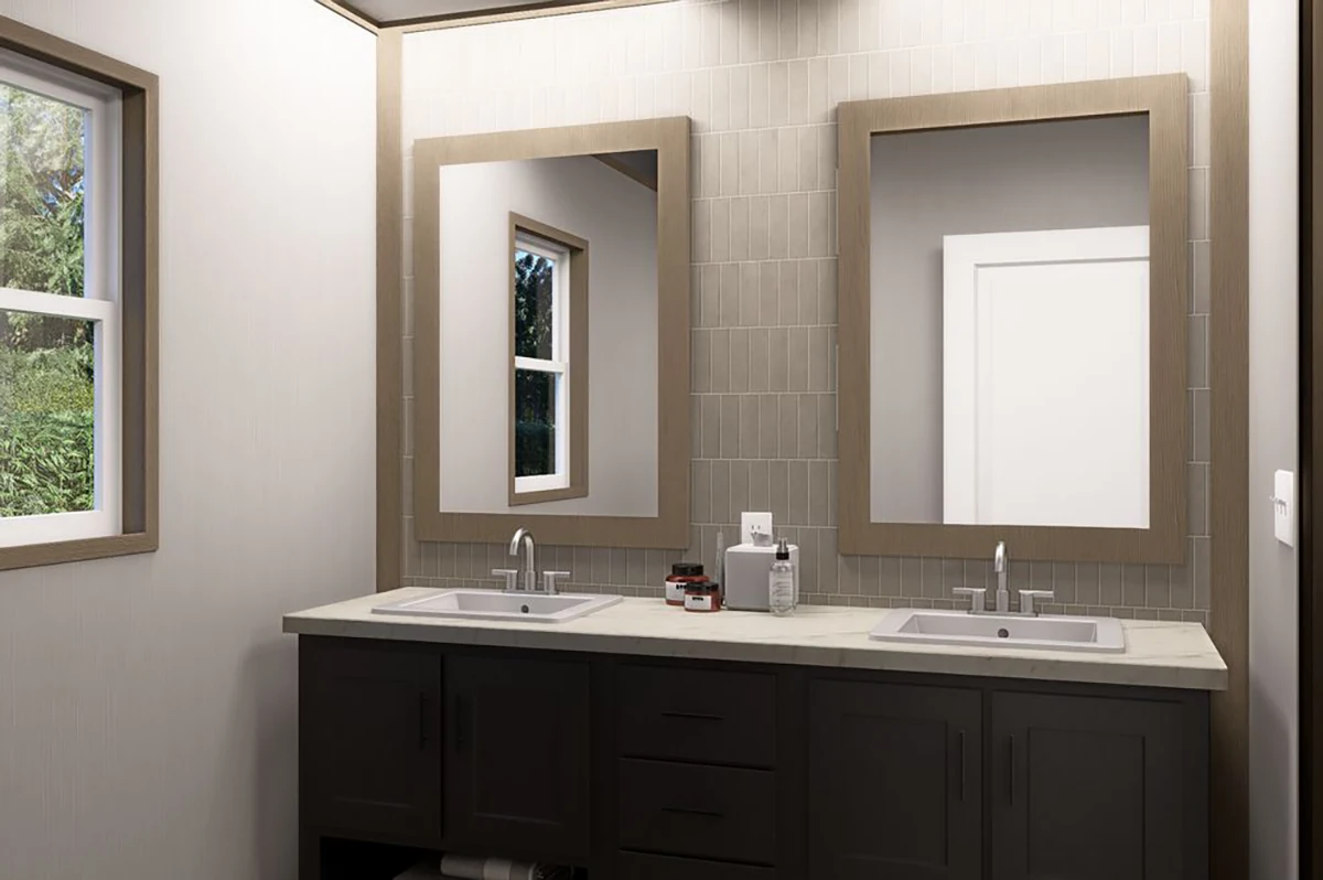 e60db66a-8da1-443b-9d18-5358b7e1822a A modern bathroom with double sinks, two rectangular mirrors, a window, and neutral-colored tile backsplash. Toiletries are arranged between the sinks on the countertop.