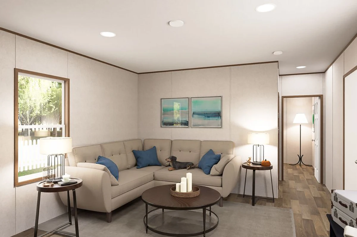 e64b6e06-40e0-4553-b6da-8f44e7a95257 A modern living room with a beige sectional sofa, a small dog, two side tables, a round coffee table with candles, and framed art on the wall; natural light enters through a window.