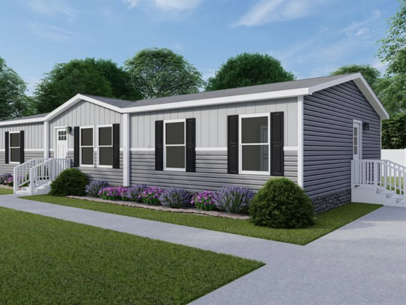 A single-story manufactured home with gray siding, white trim, black shutters, two entrances with steps, and flower beds in front, set on a lawn with trees and a white fence.