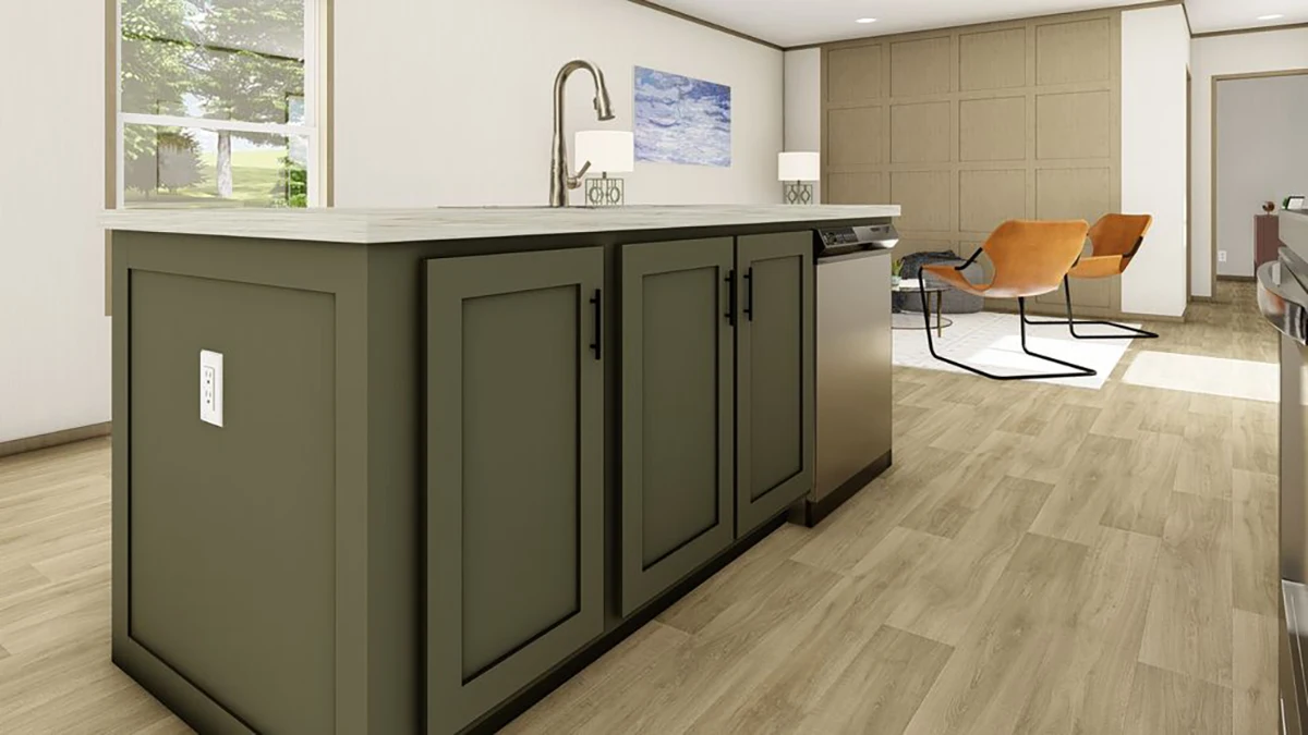 Modern kitchen with a green island, stainless steel sink, wood flooring, and an open living area with two orange chairs and wall art in the background.