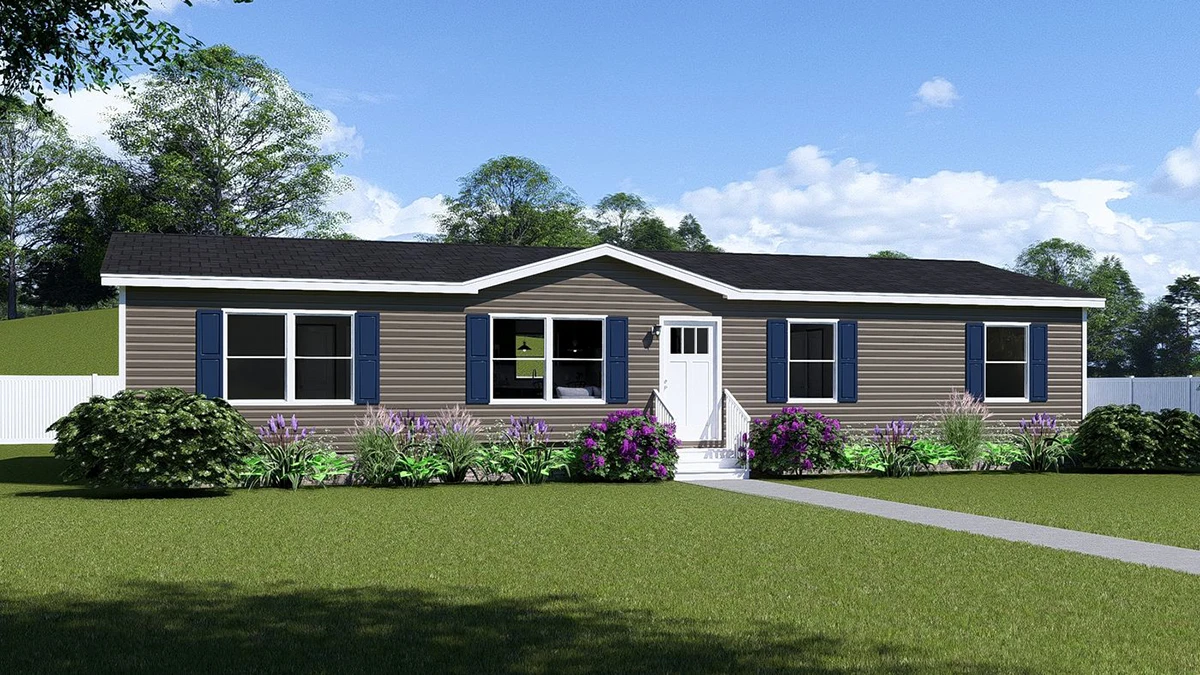 e9bc9e29-7f60-41c1-99cf-999fa2dedb04 Single-story manufactured home with beige siding, black roof, blue shutters, front steps, and landscaped yard with green grass and flowering bushes under a blue sky.