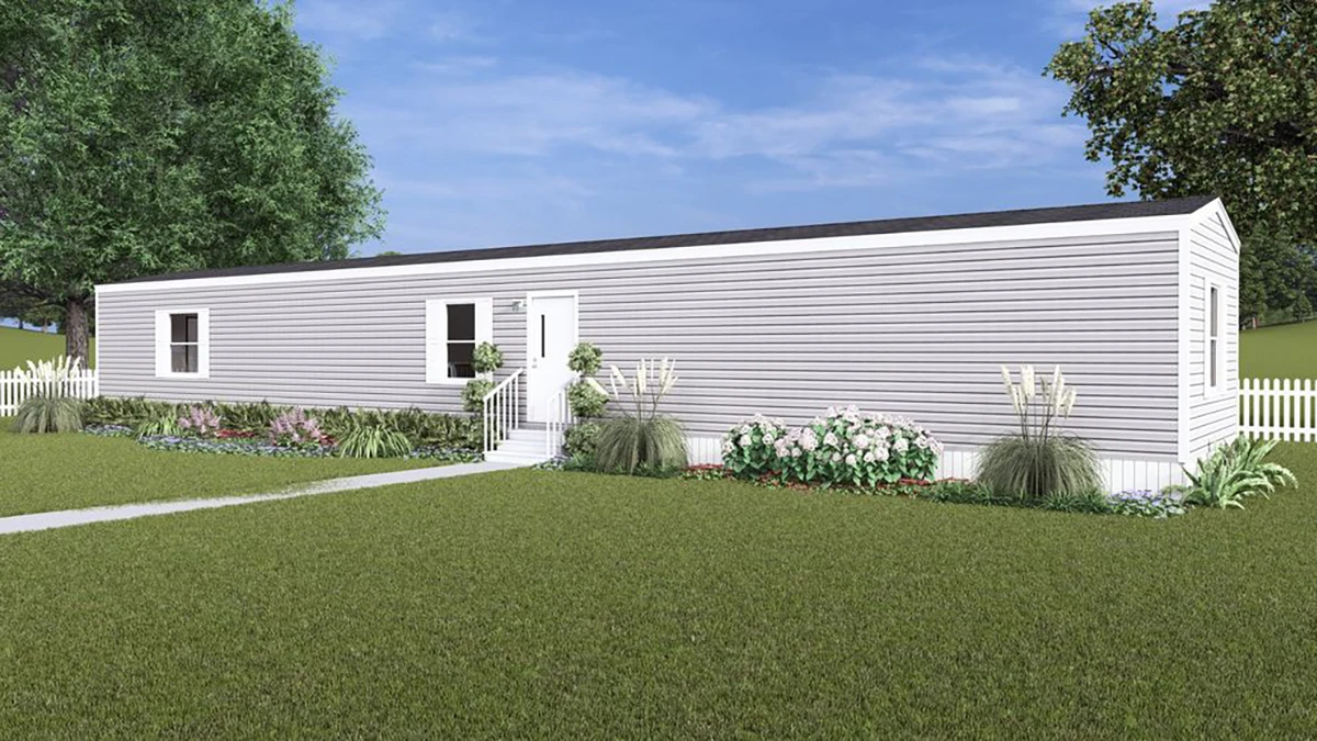 ed255a37-94d7-4888-a241-f703cea89504 A single-story, gray manufactured home with white trim, surrounded by a lawn, shrubs, flowers, and a white picket fence under a blue sky.