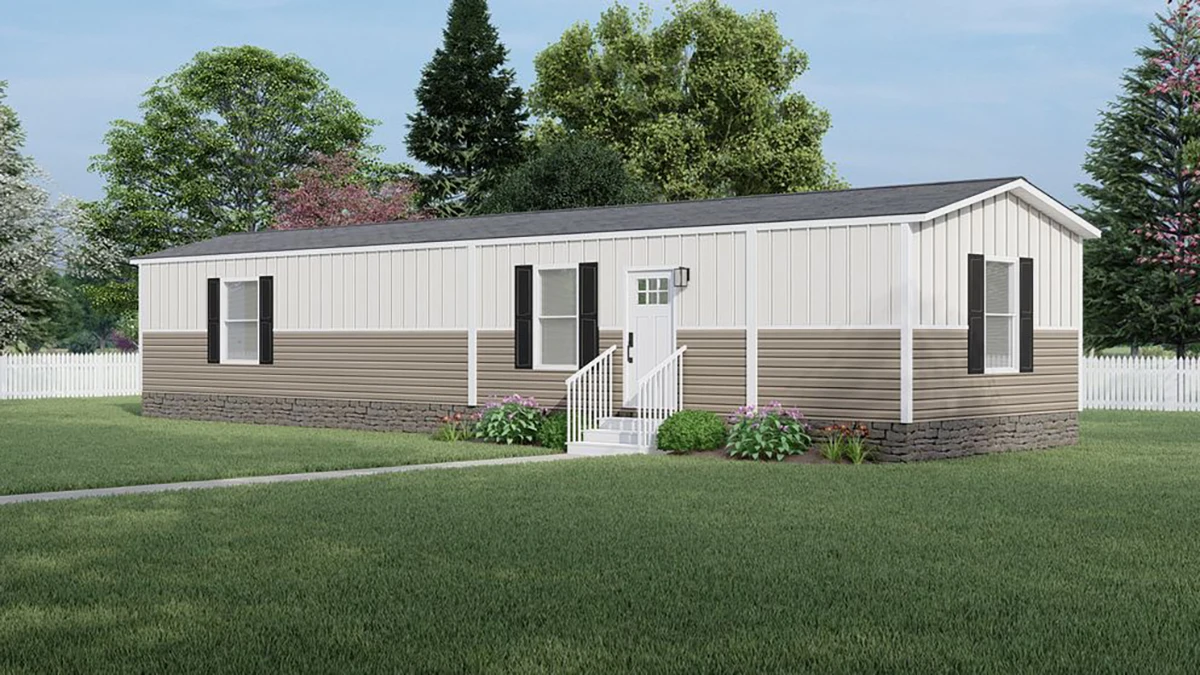 A beige and white single-wide manufactured home with black shutters, front steps, and small garden, set on a grassy lawn with trees and a white fence in the background.