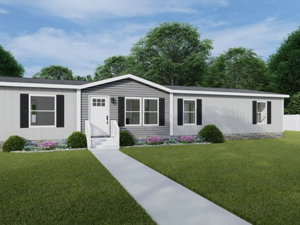 A single-story manufactured home with gray siding, black shutters, a small front porch, and a concrete walkway, surrounded by a green lawn and landscaped shrubs.