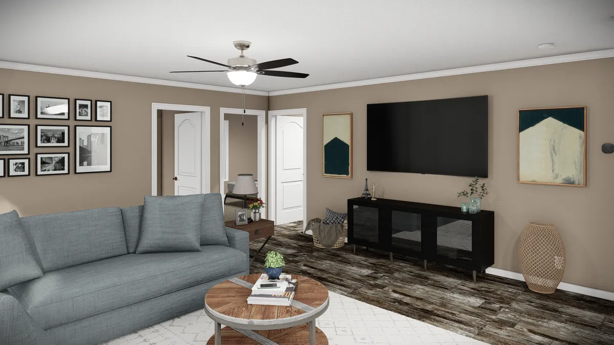 f6853f7c-0523-4c70-9e62-d706be29df13 A living room with a gray sofa, round coffee table, wall-mounted TV, sideboard, framed art, and wood-patterned floor. Ceiling fan and neutral walls complete the space.