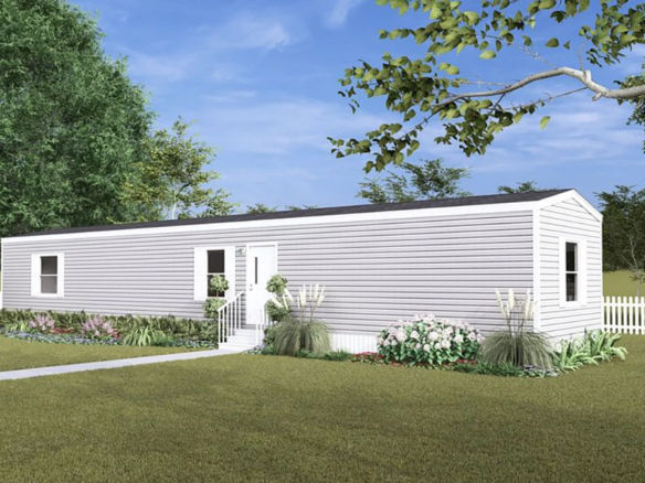 A white, single-wide mobile home with a small front garden and a white picket fence, set on a grassy lawn with trees in the background.