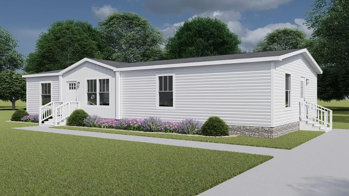 fabb99ca-5172-42d9-9bc1-e45b698c2ded A white manufactured home with a gable roof, steps leading to front and back doors, flower beds along the side, and surrounded by grass and trees under a partly cloudy sky.