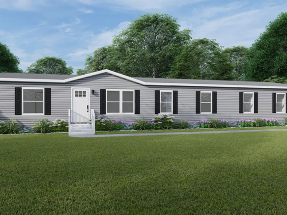 A single-story, gray manufactured home with black shutters and a small porch, surrounded by green lawn and trees under a blue sky.