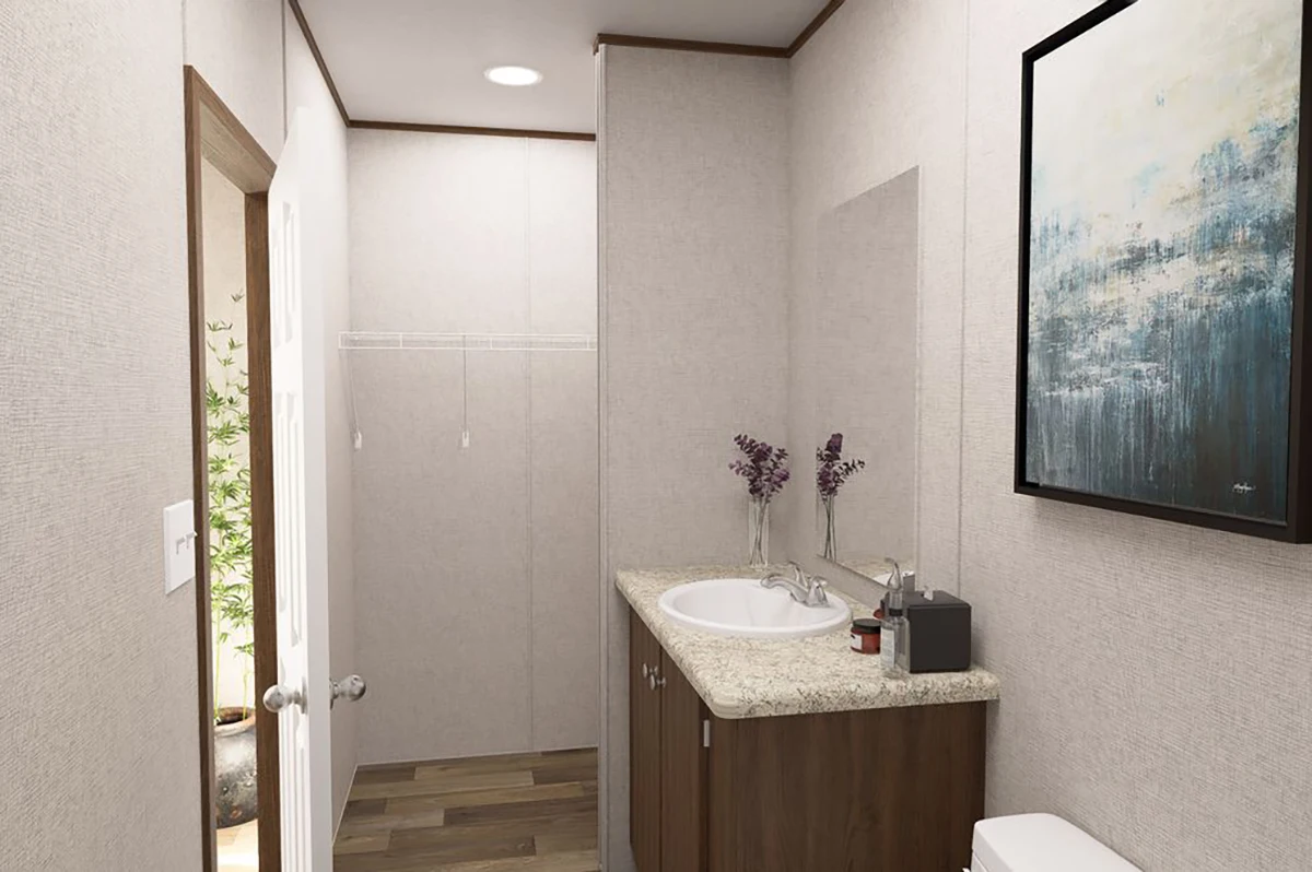 A small bathroom with a granite countertop, sink, mirror, and decorative vases; there is a framed painting on the wall and a door leading outside.