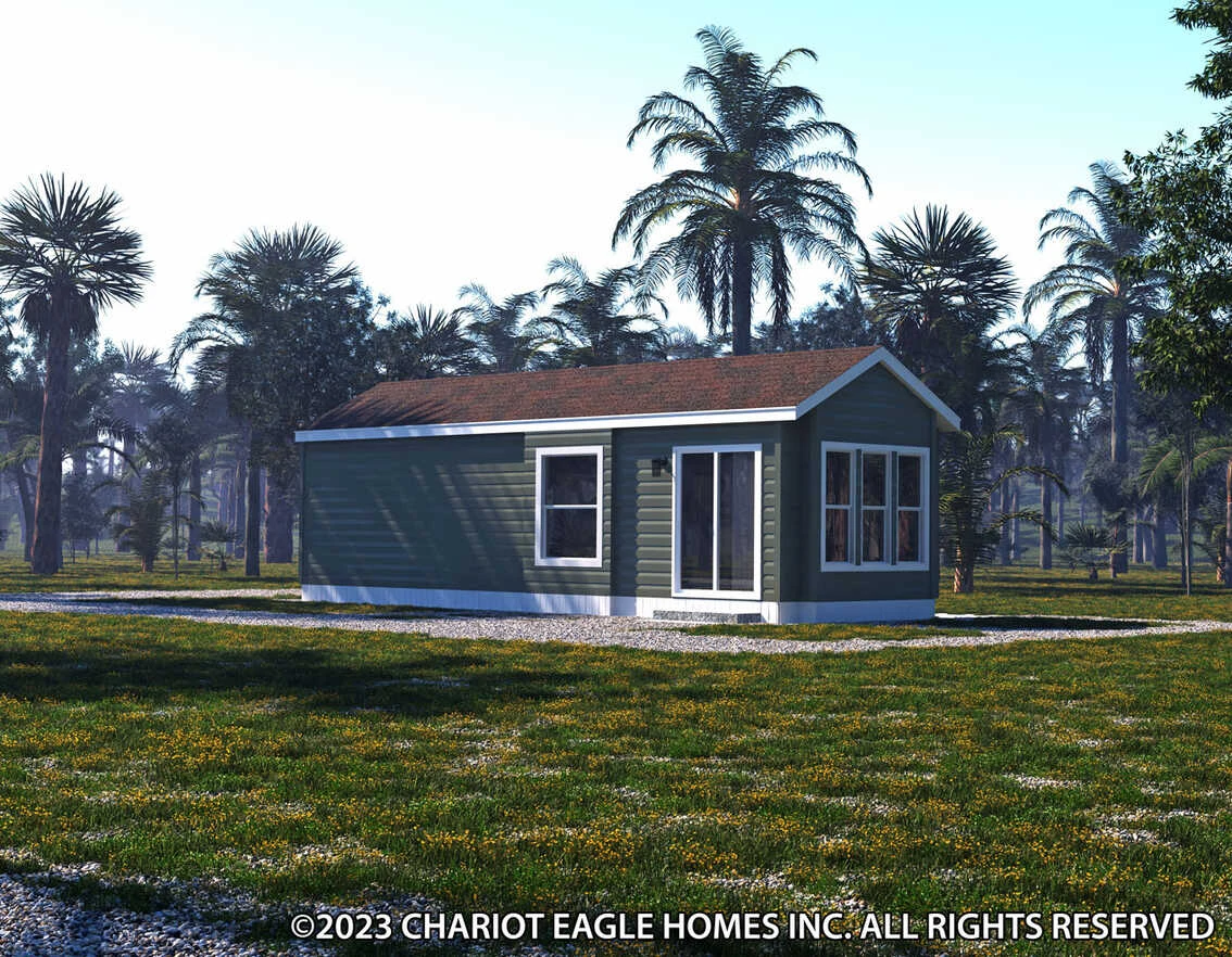 A small green manufactured home with white trim sits on a grassy lot surrounded by palm trees under a clear sky.