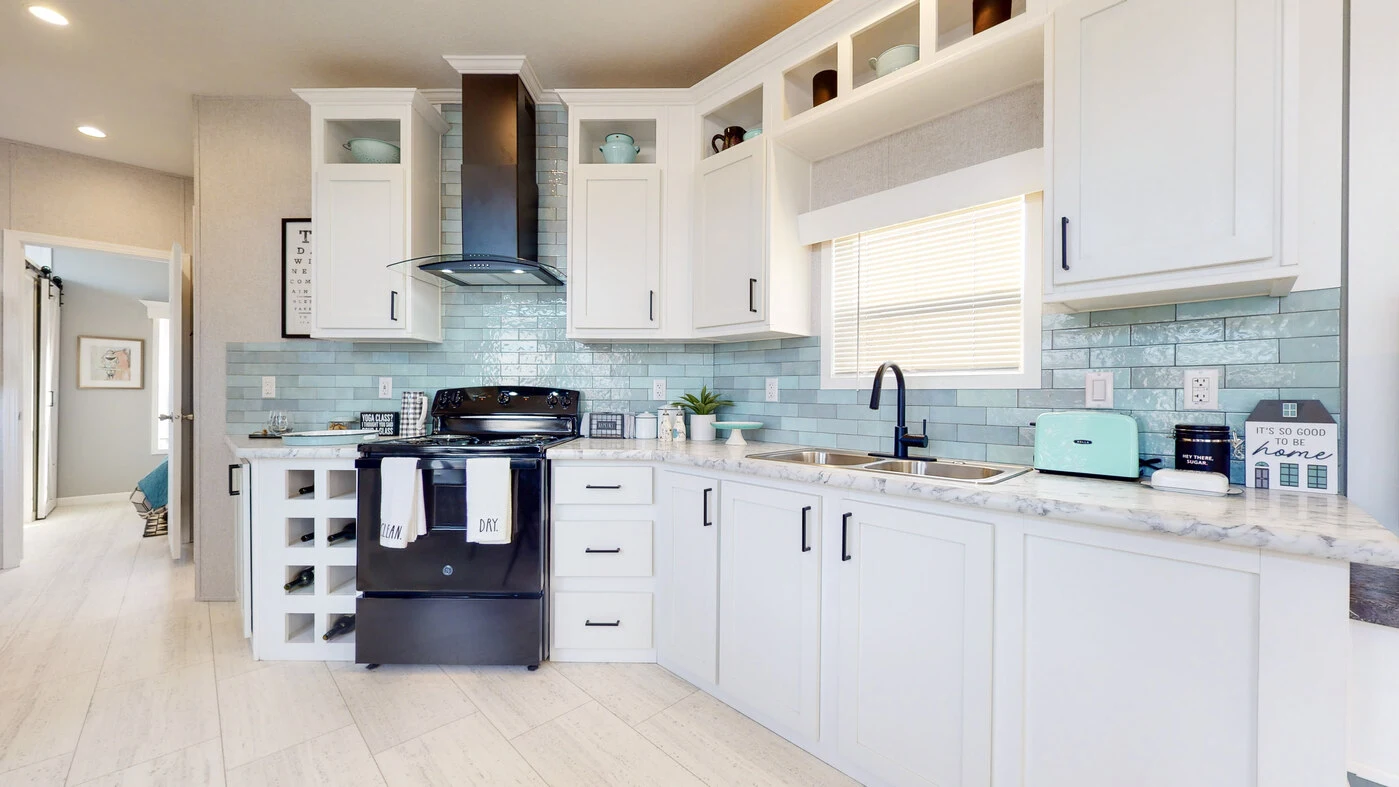 Modern kitchen with white cabinets, marble countertops, black appliances, teal backsplash tiles, wine rack, and a window with blinds above a double sink.